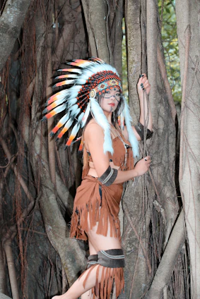 A serene indigenous elder in traditional attire standing in a lush forest, symbolizing cultural strength and nature.