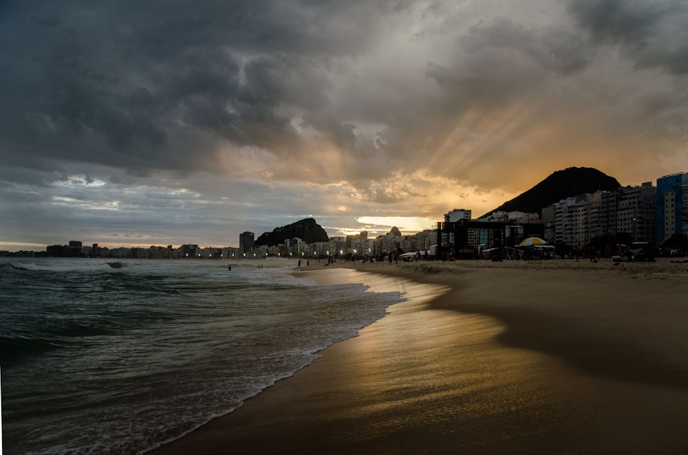 the sun is setting over a beach with buildings in the background