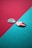 Two guitar picks rest on a surface divided diagonally by contrasting colors, one teal and the other a deep red hue. The picks lie on opposite colors, with one pick a light green, featuring a textured pattern, and the other pink, with a smoother finish.