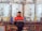 A person stands in front of large, industrial machinery with several cylindrical tanks. The machinery has a utilitarian design with visible pipes and valves. The person is wearing a red and black jacket, standing on a platform with railings.