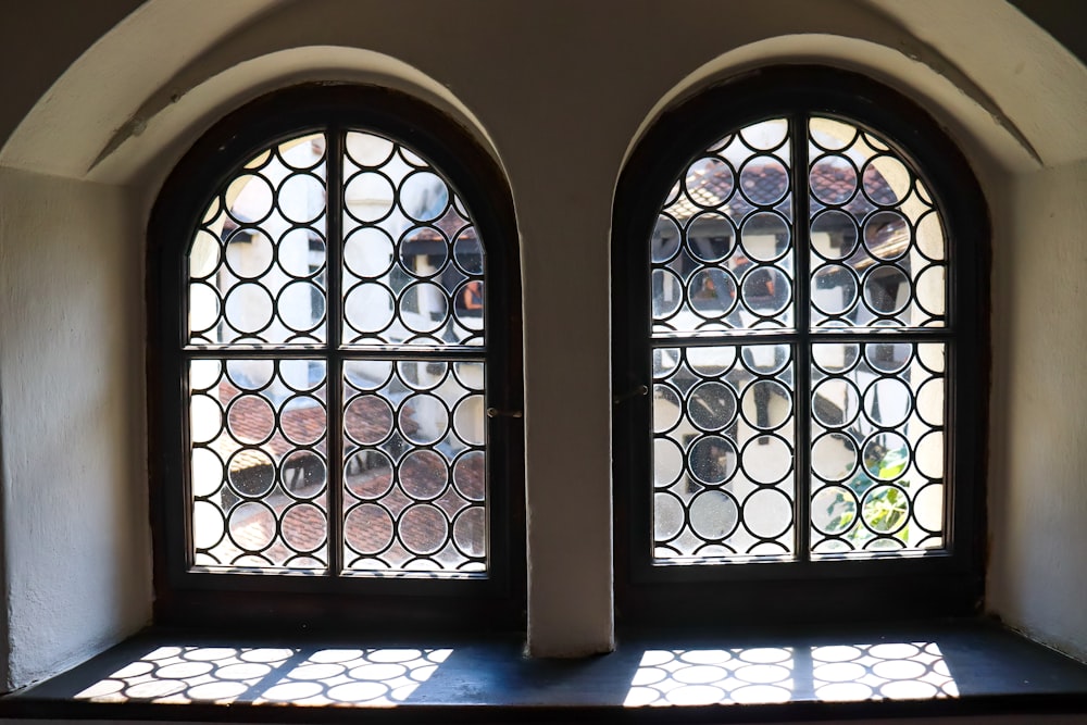 two arched windows in a building with sunlight coming through them