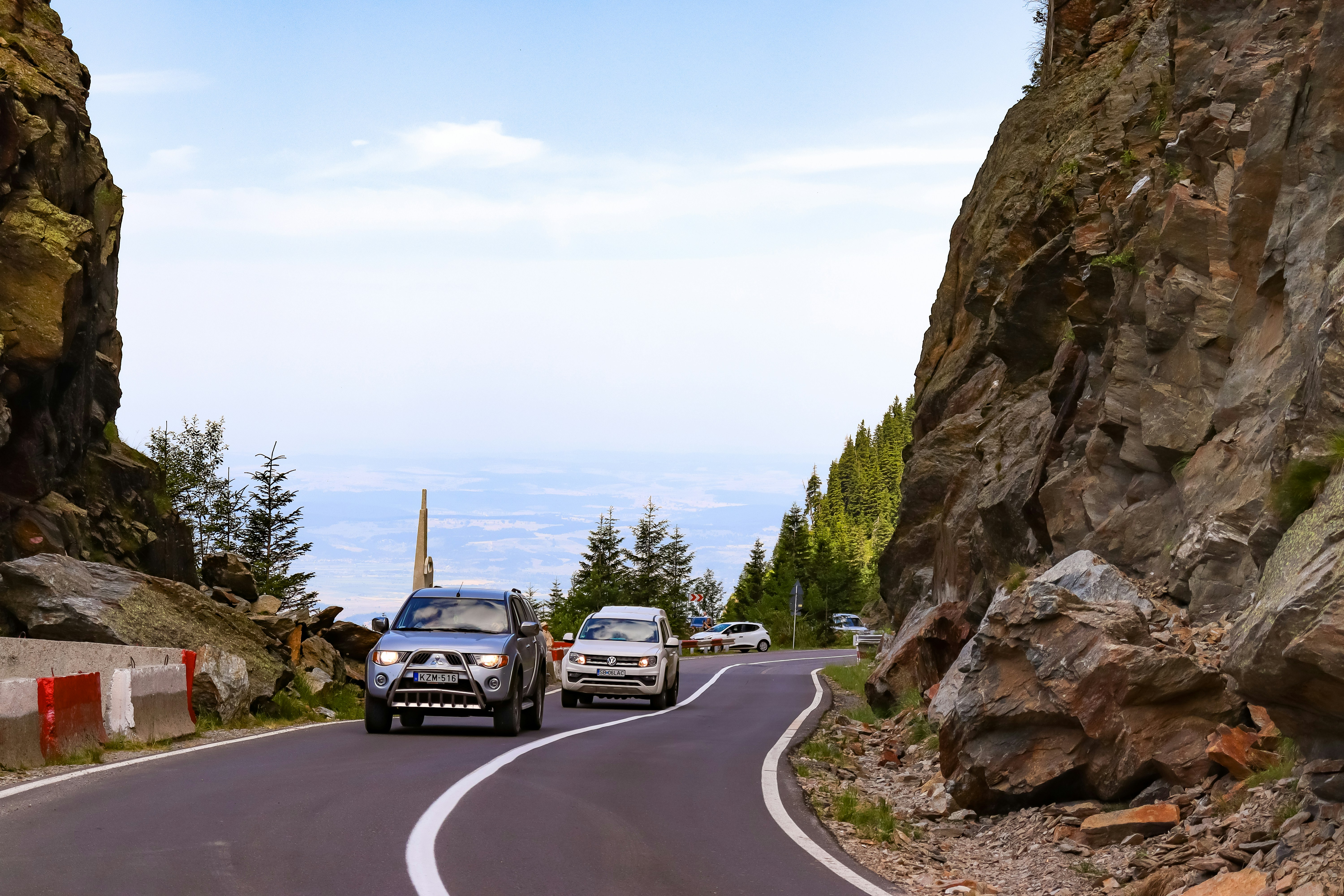 a couple of cars driving down a mountain road