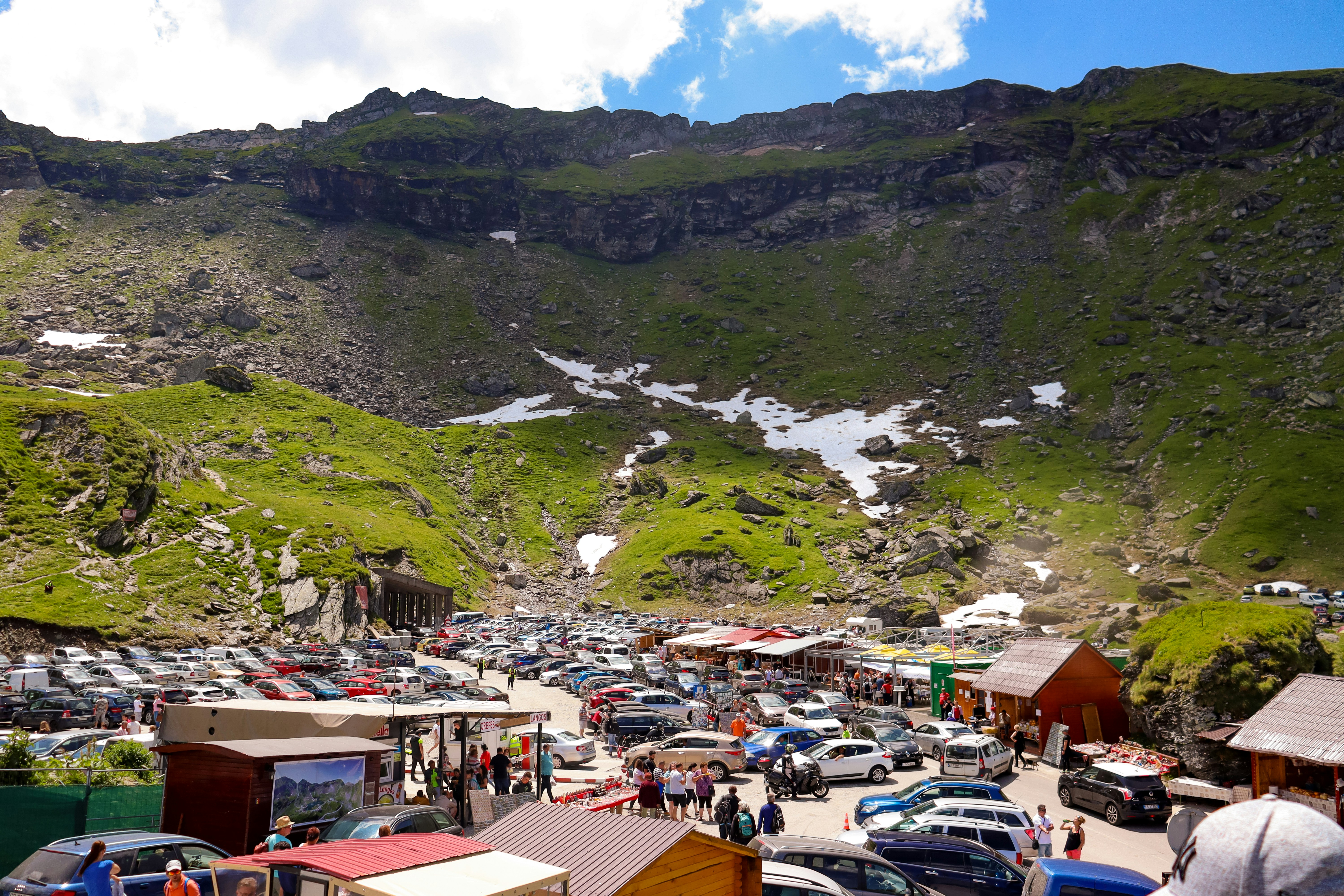 a group of cars parked in a parking lot next to a mountain