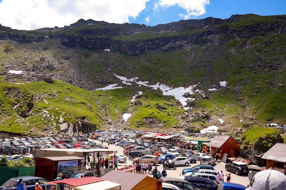 a group of cars parked in a parking lot next to a mountain