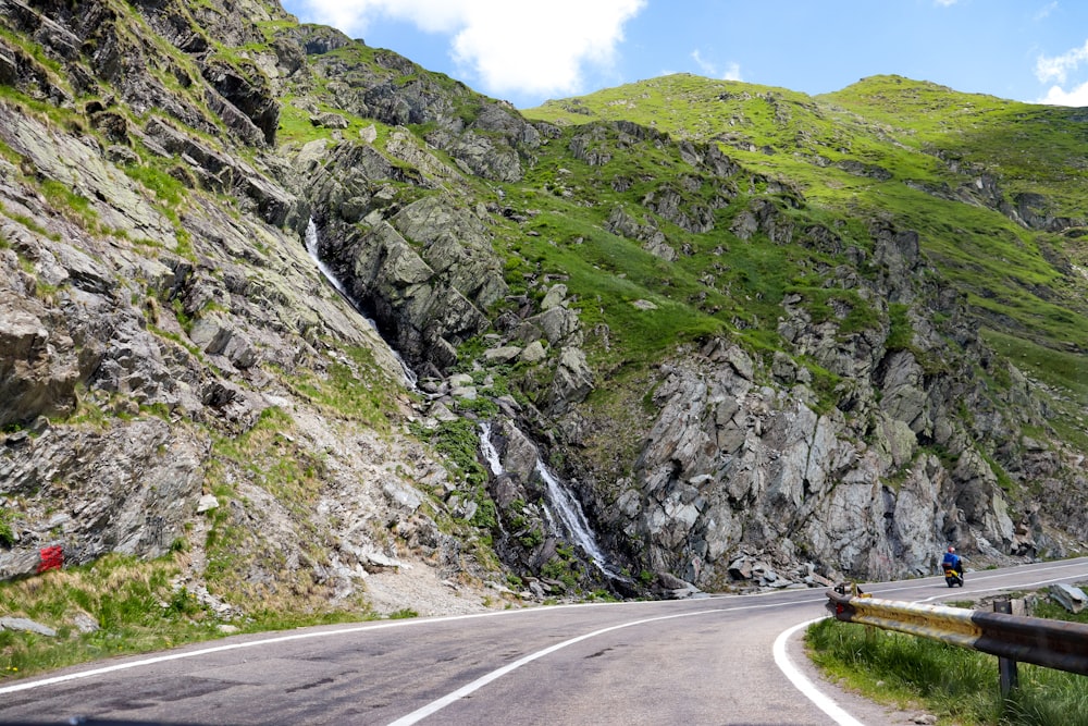 a winding road with a waterfall on the side of it