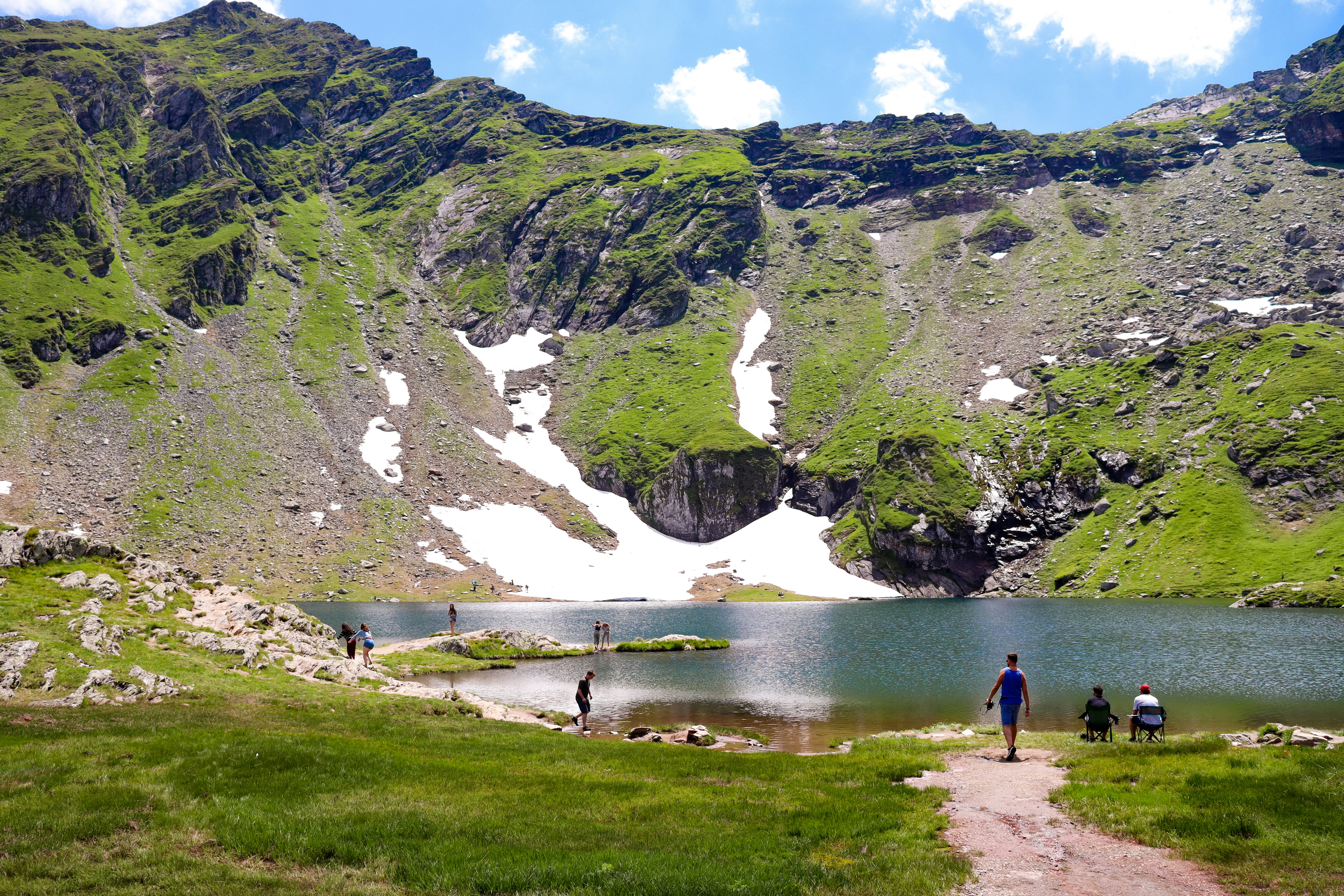 a group of people walking up a hill next to a lake