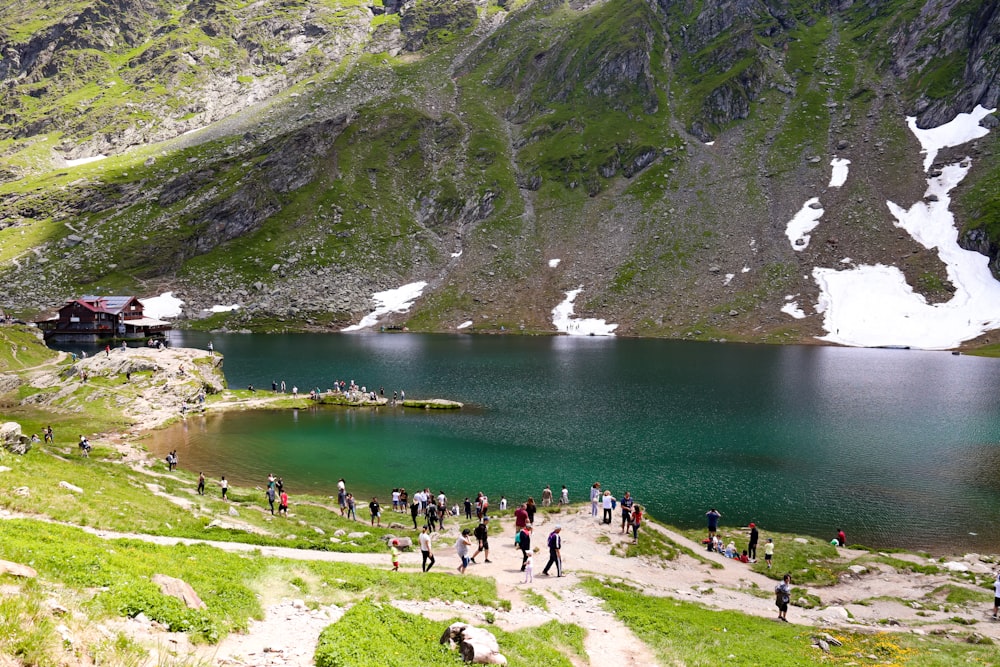 a group of people walking up a hill next to a lake