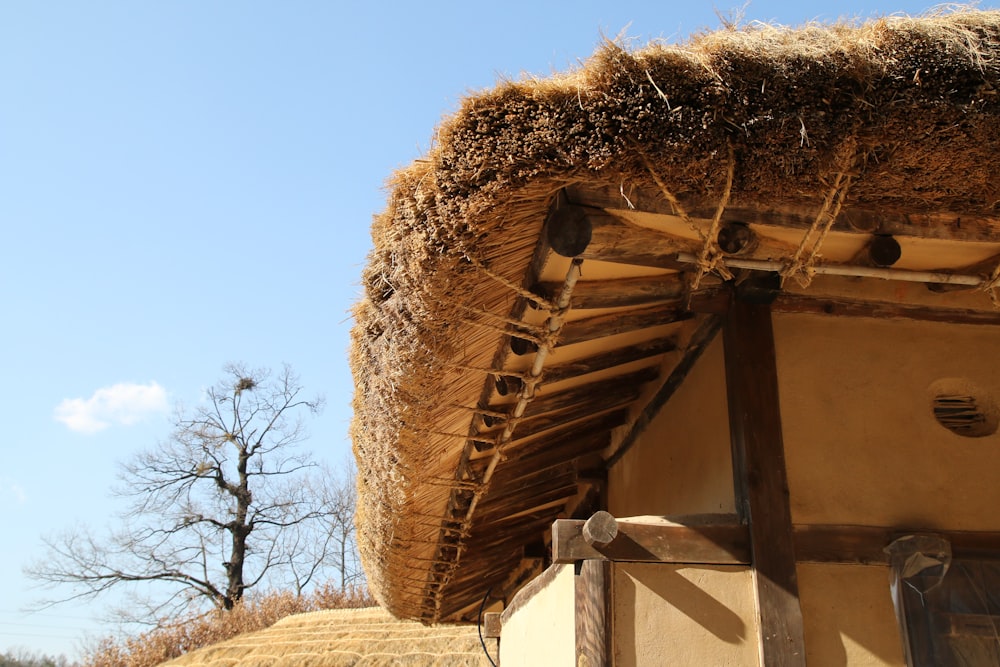a thatched roof on a building with a tree in the background