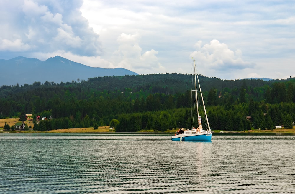 a sailboat floating on a lake with a mountain in the background