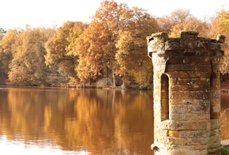 a brick tower sitting on top of a lake surrounded by trees