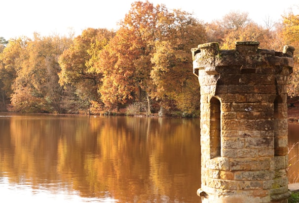 a brick tower sitting on top of a lake surrounded by trees