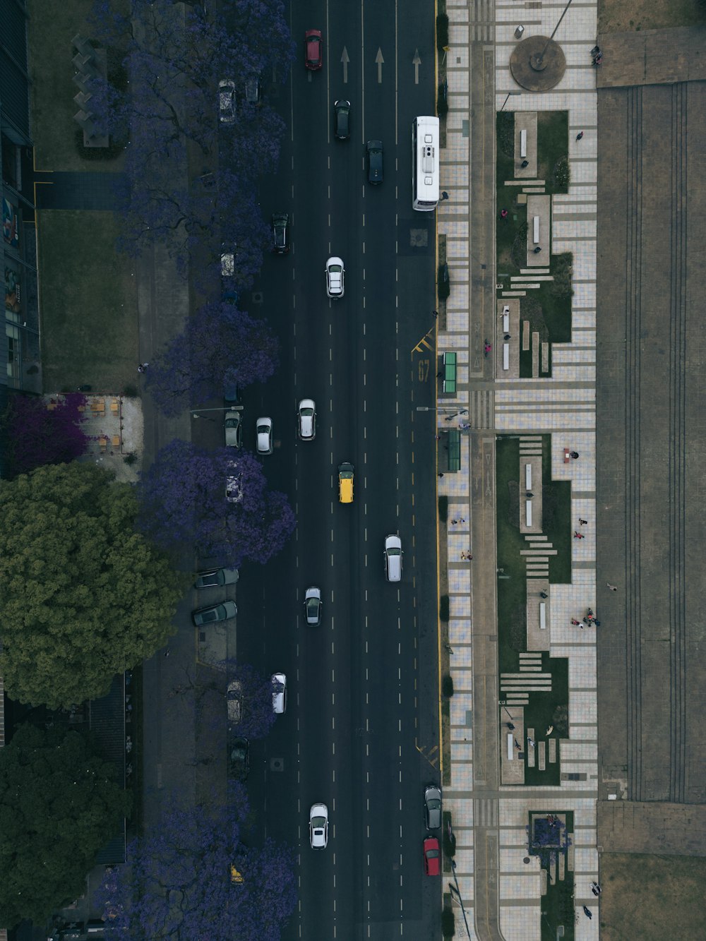 an aerial view of a street with cars parked on the side of the road
