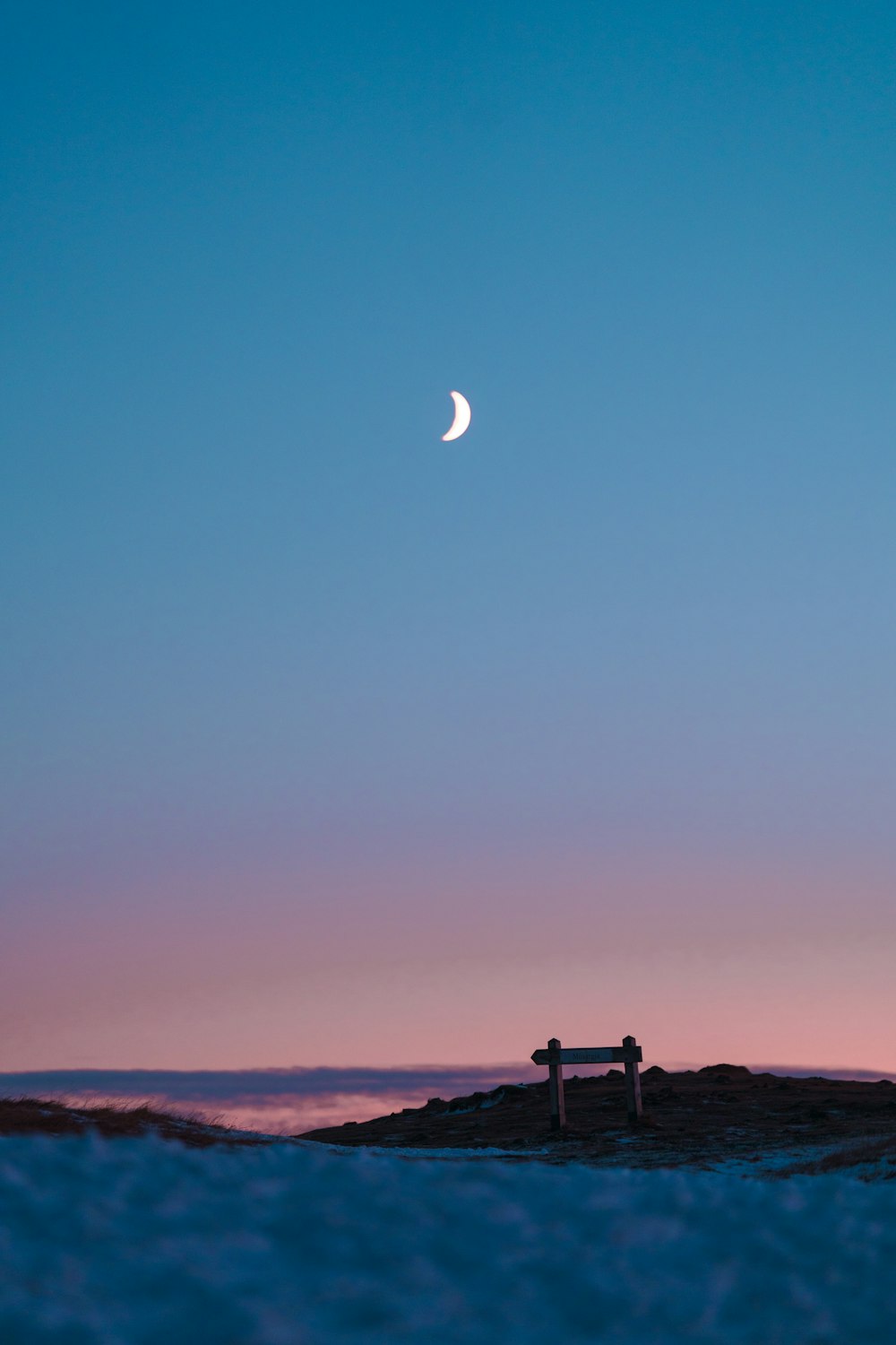 a bench sitting on top of a sandy beach under a moon