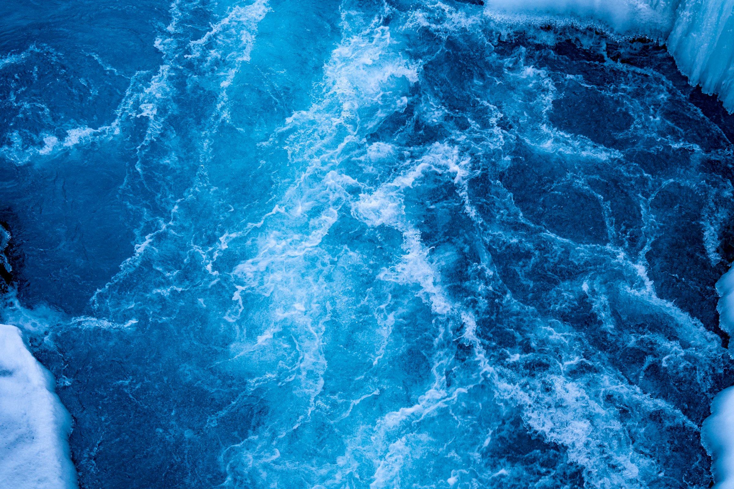 Błękitna woda wirująca między lodem