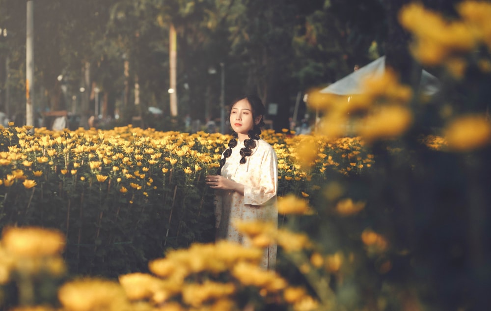 a woman standing in a field of yellow flowers