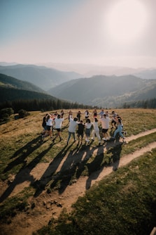a group of people standing on top of a lush green hillside