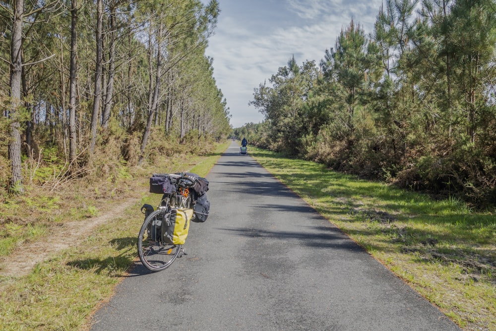 a bike parked on the side of a road next to a forest