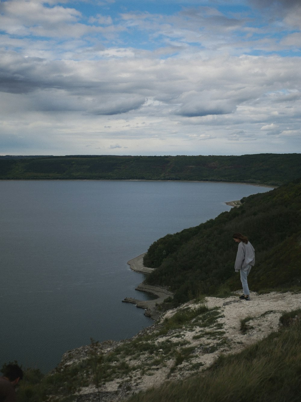 a man standing on top of a hill next to a body of water