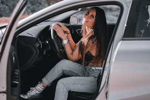 Smiling driver adjusting the car radio while cruising on a sunny highway.