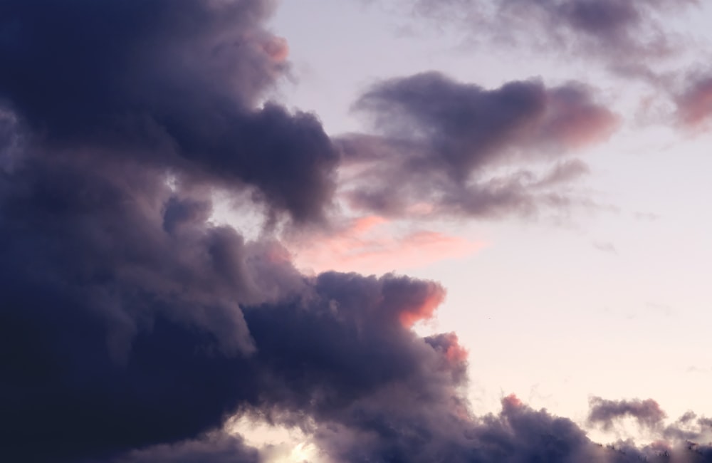 a plane flying through a cloudy sky at sunset