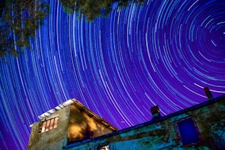 A time-lapse photo showing star trails circling around the North Star over a quiet observatory.