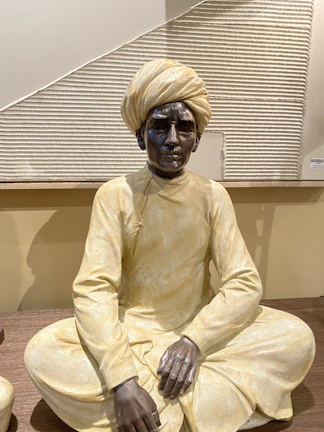 Portrait of the institute's founder in traditional Indian attire, seated in a study lined with ancient manuscripts.