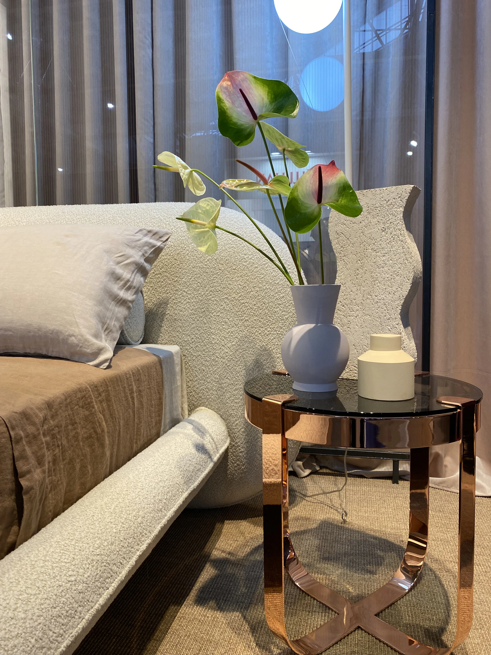 A serene modern bedroom featuring a soft beige upholstered bed, wooden side tables, and warm ambient lighting that highlights the elegant textures.