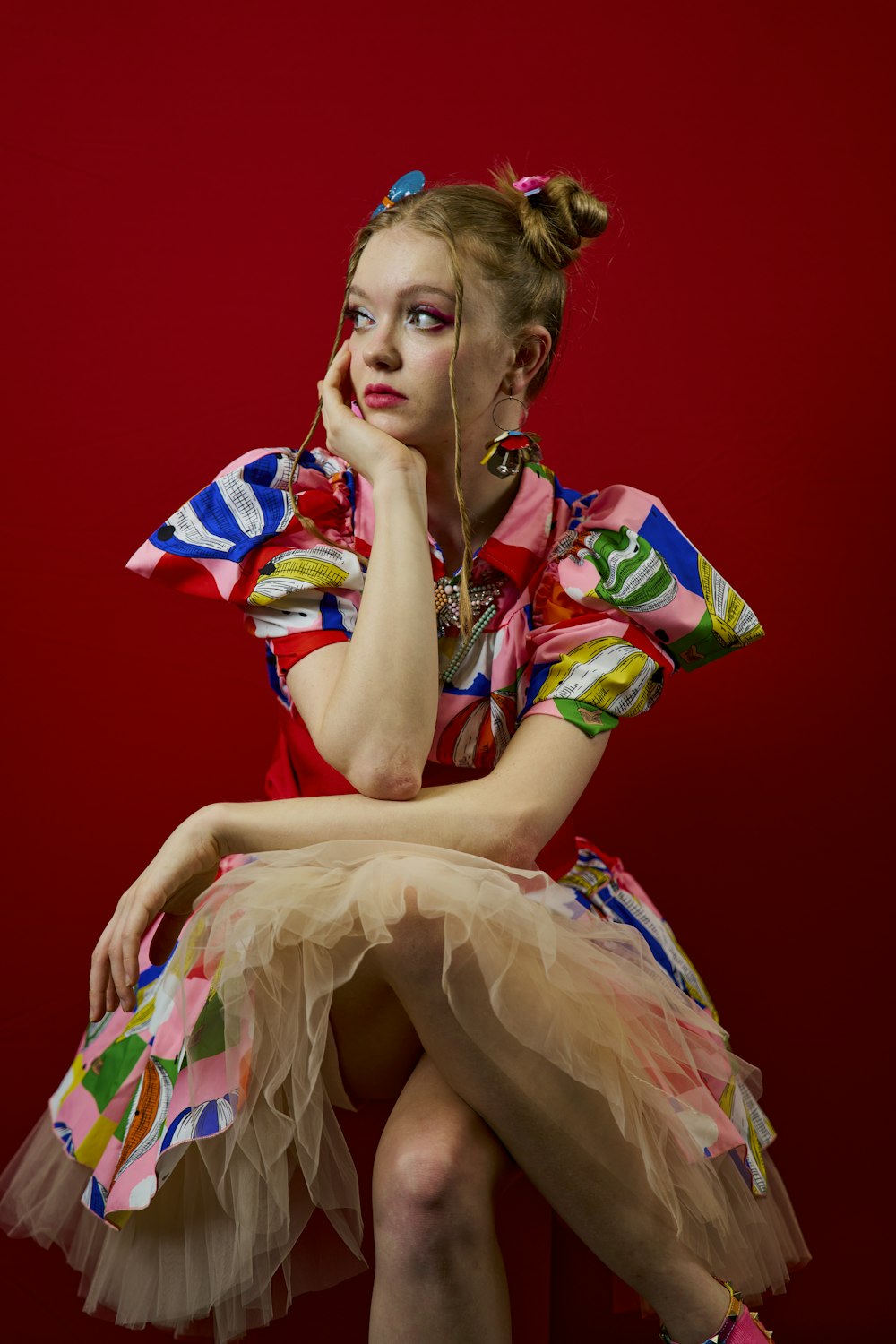 a woman in a colorful dress sitting on a stool