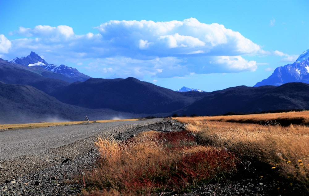 a dirt road surrounded by mountains under a blue sky