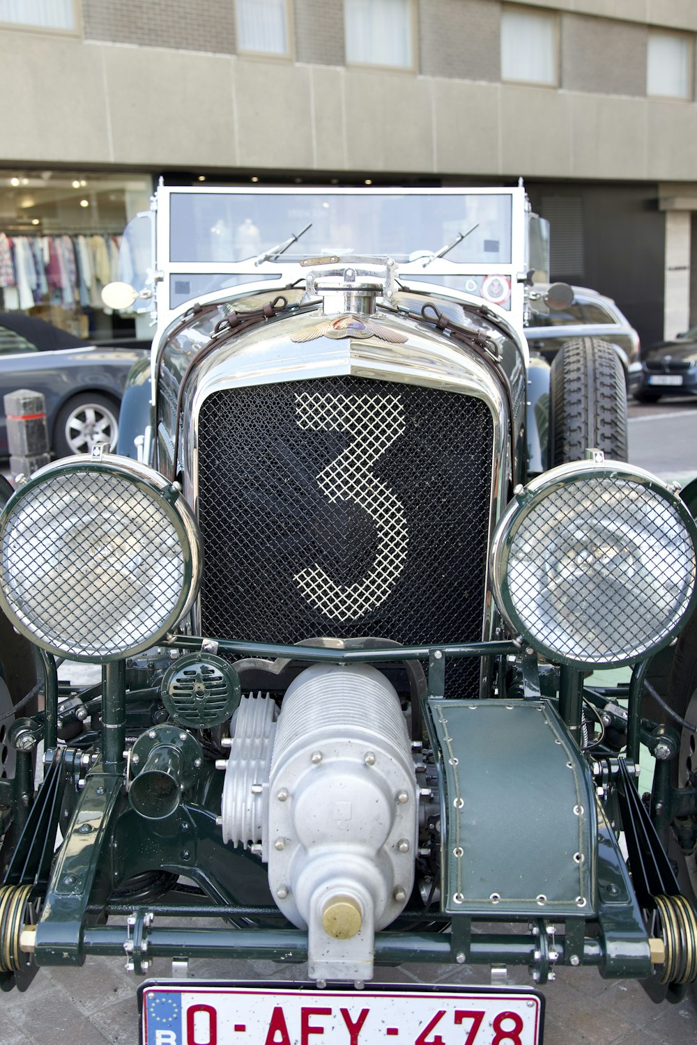 the front of an antique car parked on the side of the road