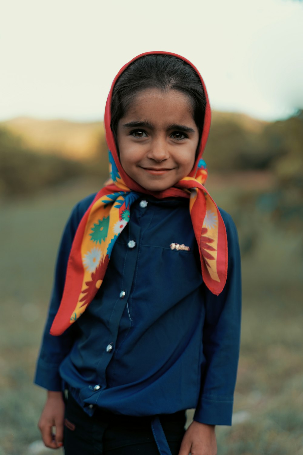 a young girl wearing a blue shirt and a colorful scarf
