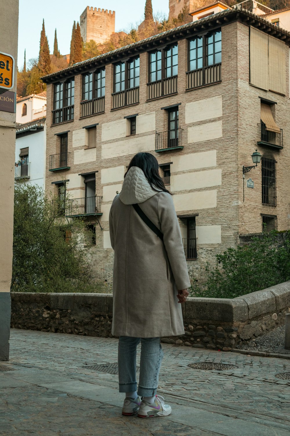 a woman walking down a street past a tall building