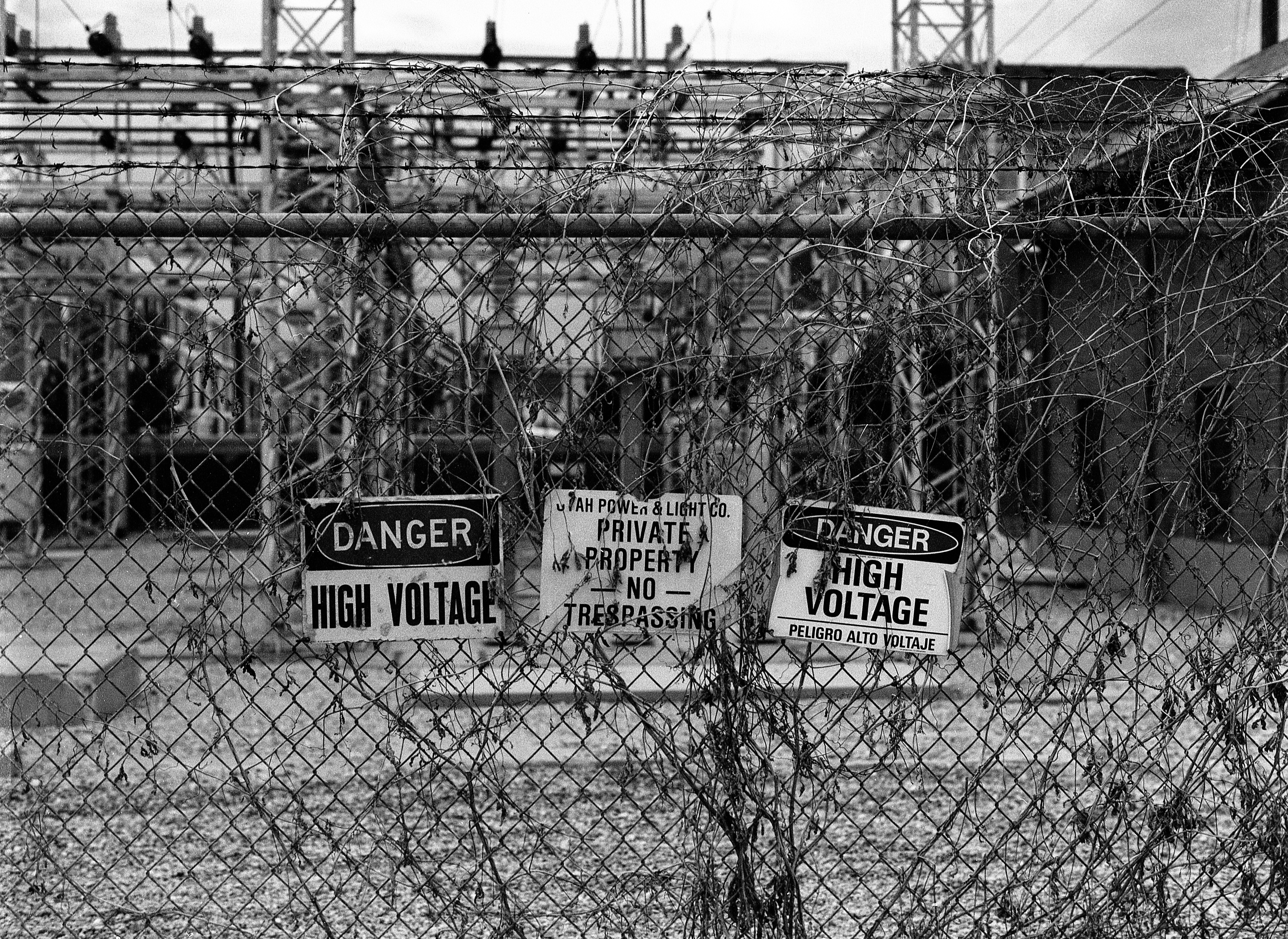 a black and white photo of a fence with signs on it