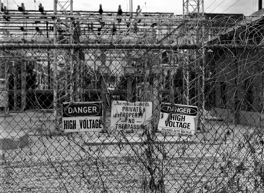 a black and white photo of a fence with signs on it