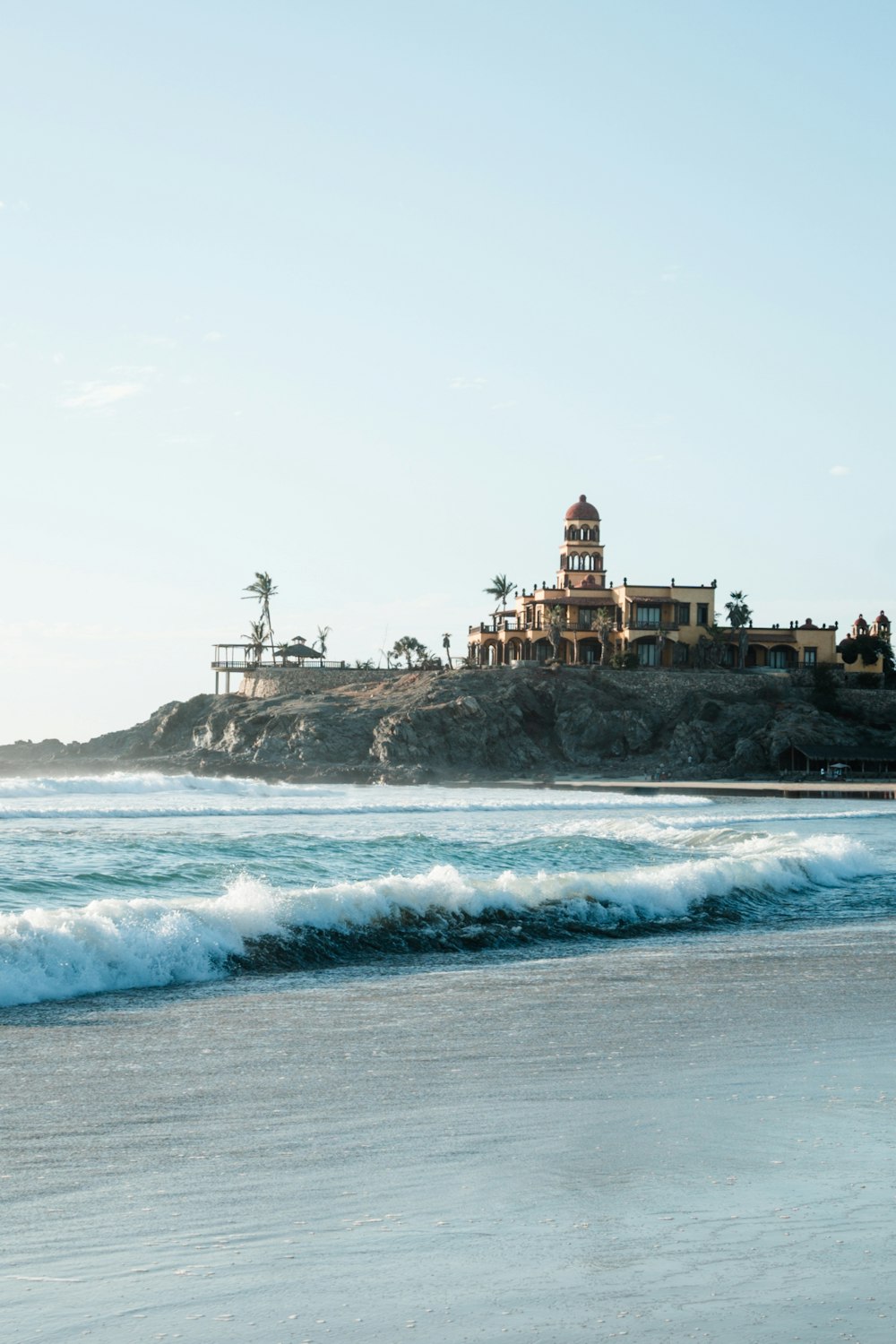 a beach with waves crashing in front of a building