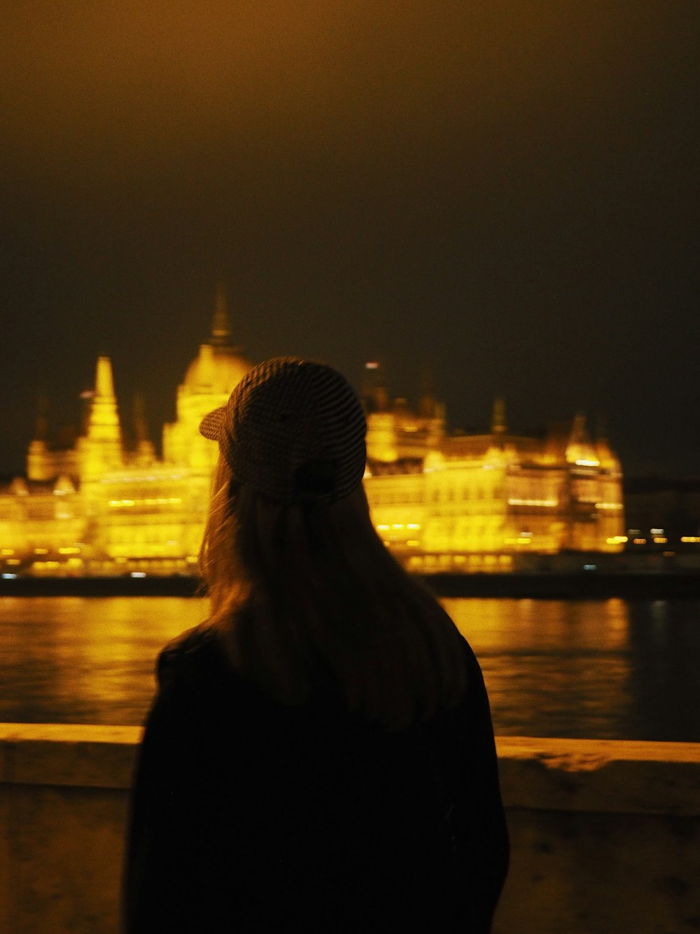 a woman standing in front of a body of water at night