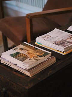 a stack of magazines sitting on top of a wooden table