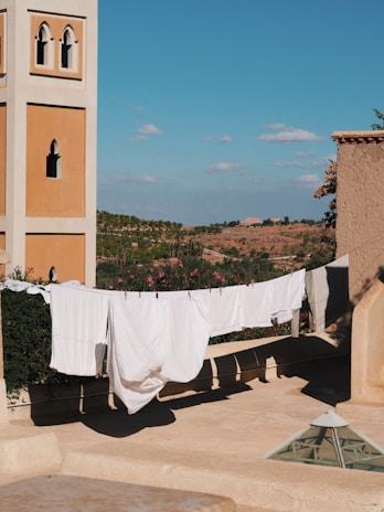 Outdoor scene of clothes drying on a line under a clear blue sky, with Blisso detergent packaging visible nearby.