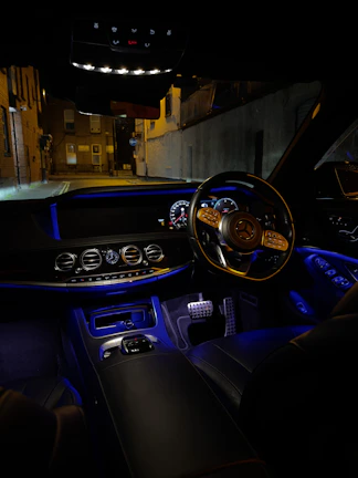 Luxury car interior illuminated by subtle electric blue ambient lighting highlighting the dashboard.