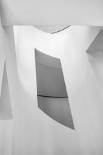 Grayscale image of modern architectural structure emphasizing sharp angles and empty space.