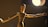 A wooden artist mannequin with articulated joints stands with its arms outstretched under a bright spotlight. The lighting creates dramatic shadows on the mannequin and highlights its wooden texture.