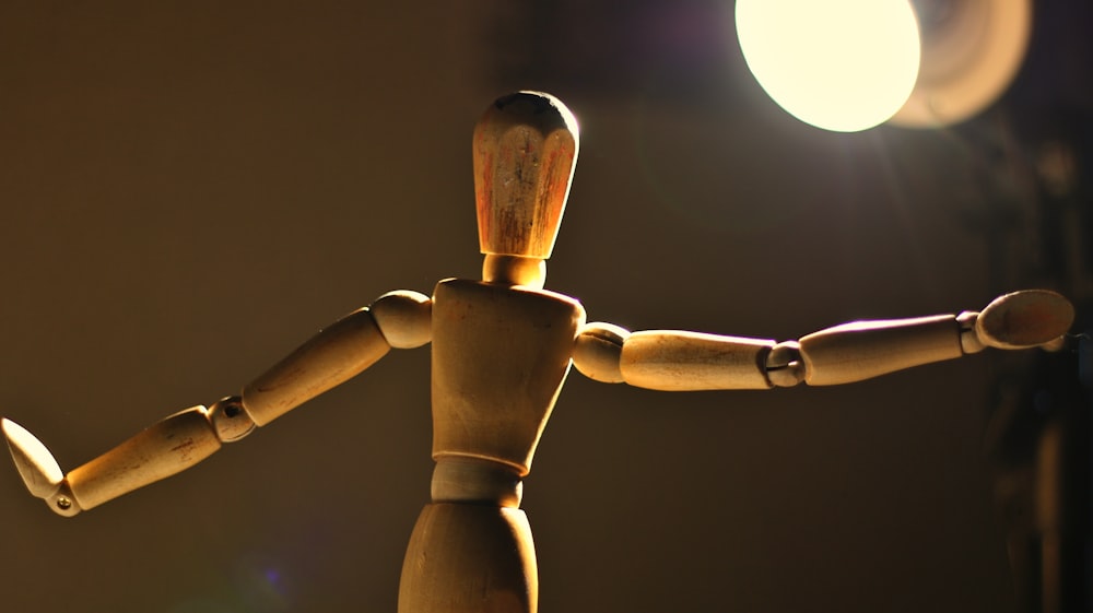 a wooden toy standing in front of a light