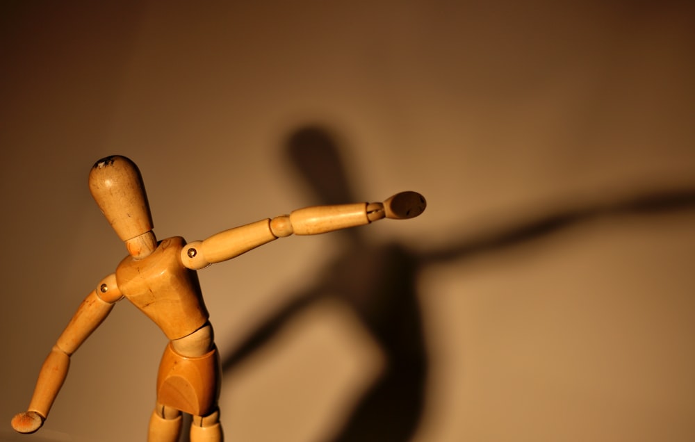 a wooden toy with a long shadow on a wall