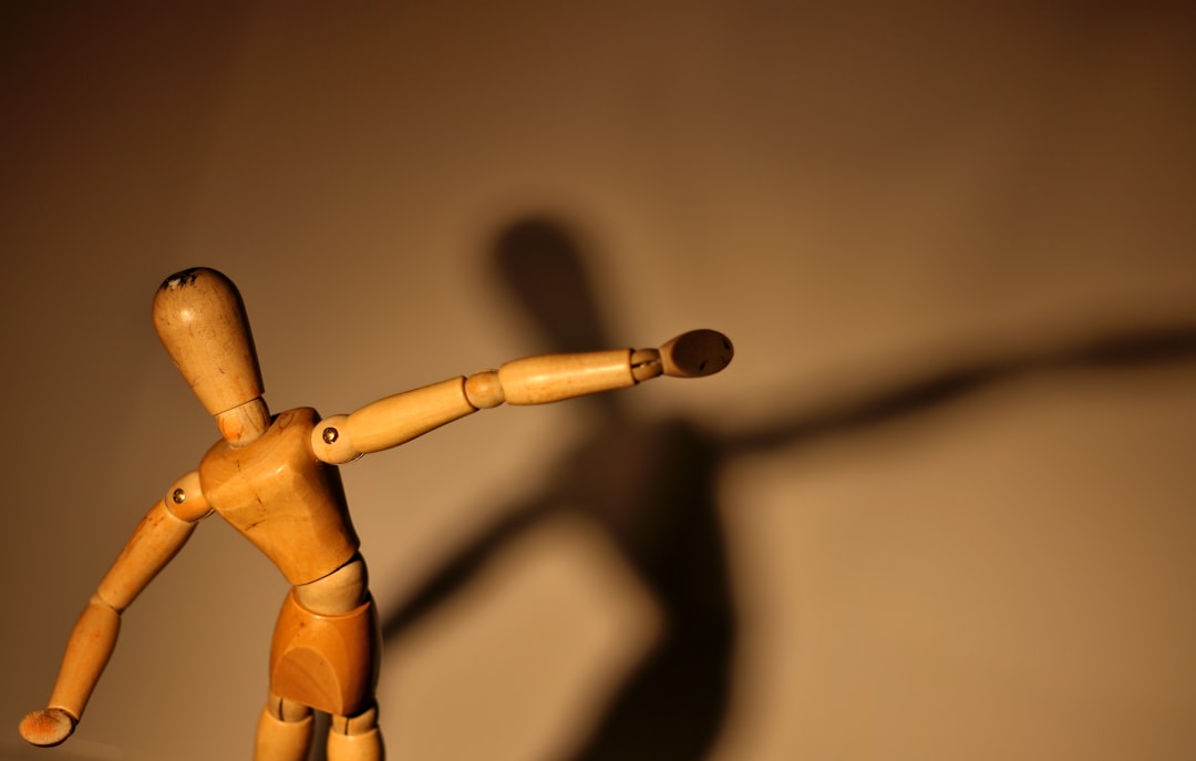 a wooden toy with a long shadow on a wall, Mannequin dancing