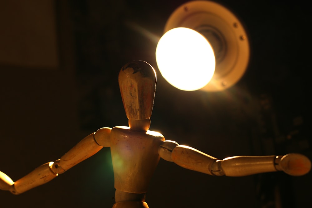 a wooden mannequin standing in front of a light