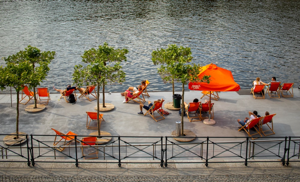 a group of people sitting on lawn chairs next to a body of water