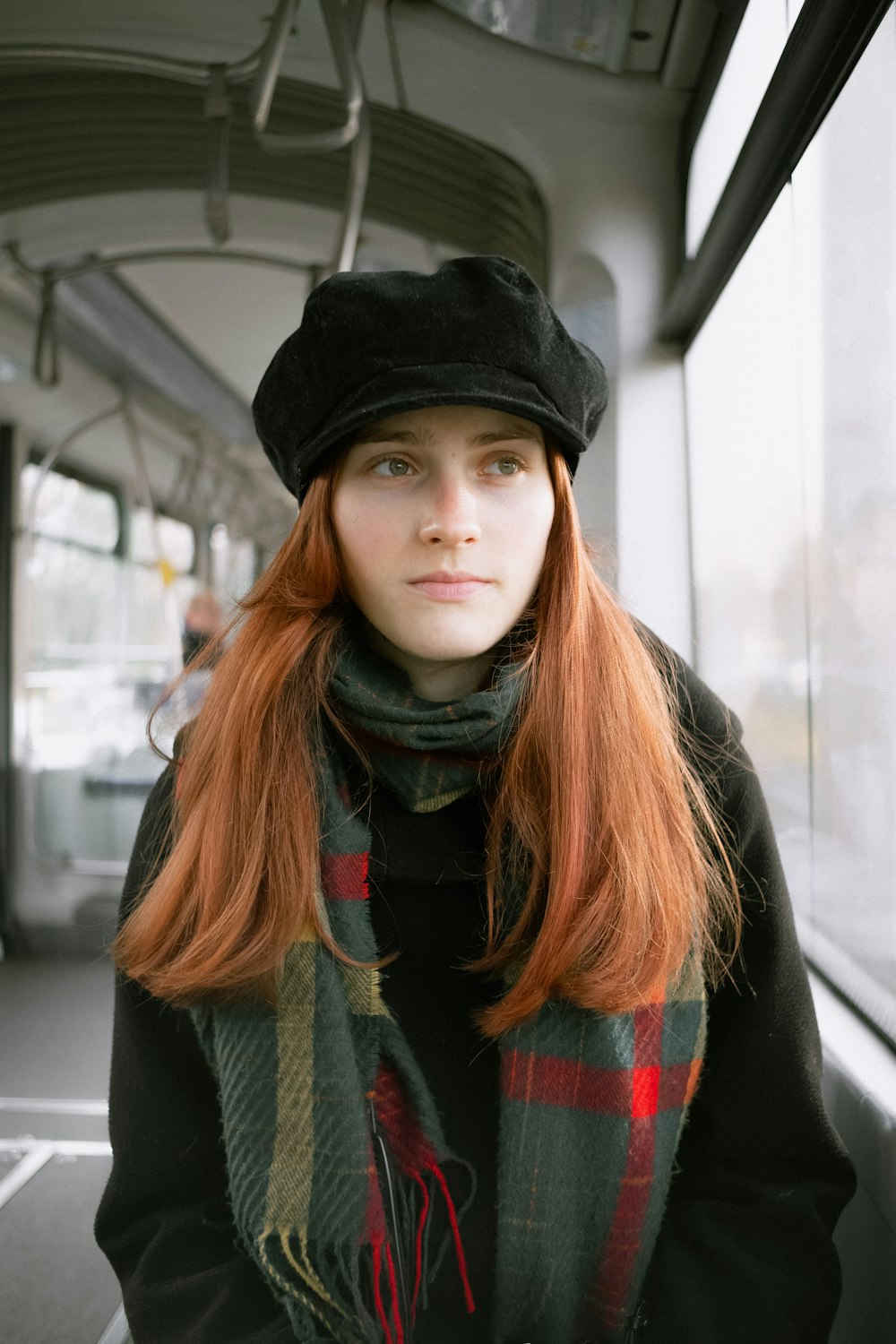 a woman with red hair wearing a black hat and scarf
