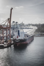 A cargo ship loaded with chemical containers departing a busy port.