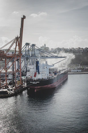 A cargo ship loaded with steel products ready to depart from a busy port.