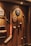 A variety of sports memorabilia displayed on a wooden wall, including a hockey stick, cricket bat, golf clubs, plaques, and balls. The lighting casts warm tones and highlights the vintage and rustic feel of the items.